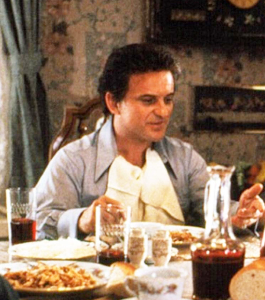 Joe Pesci and a cluttered table filled with bread and pasta in one of his many iconic film roles.