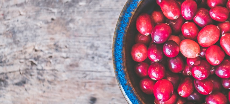 A bowl of cranberries on a wooden surface.